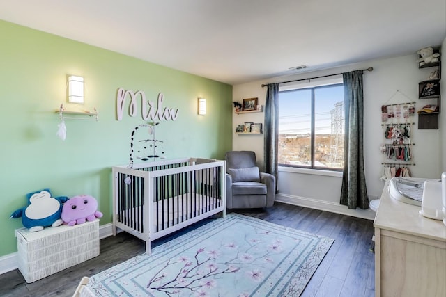 bedroom with a crib and dark hardwood / wood-style floors