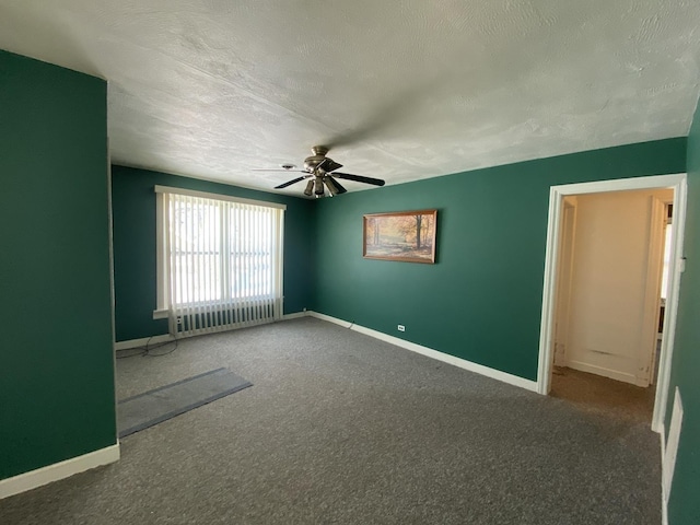 spare room featuring dark colored carpet, ceiling fan, and a textured ceiling