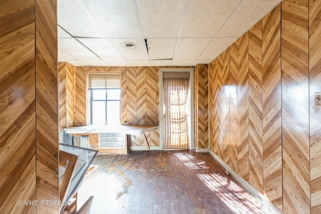 miscellaneous room with hardwood / wood-style flooring, a paneled ceiling, and wooden walls