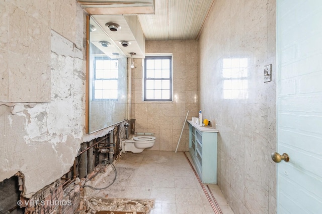 bathroom with tile walls and toilet