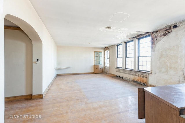 empty room featuring radiator heating unit and light wood-type flooring