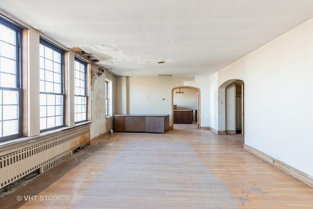 unfurnished room featuring radiator and light hardwood / wood-style flooring