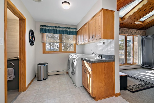 clothes washing area featuring a skylight, a baseboard radiator, cabinets, and a healthy amount of sunlight