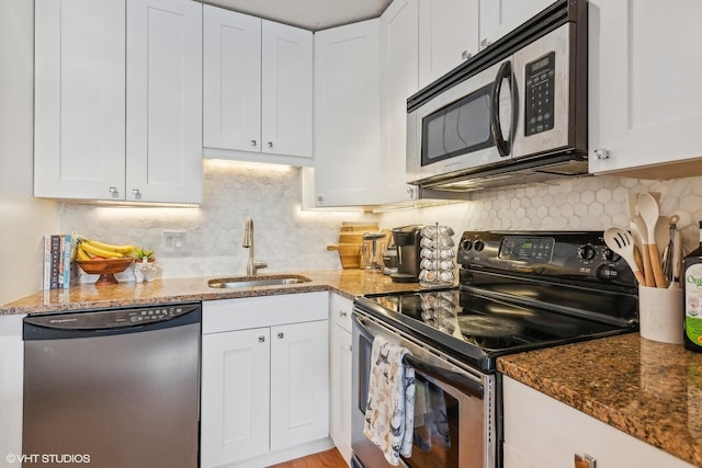 kitchen featuring appliances with stainless steel finishes, sink, dark stone counters, and white cabinets