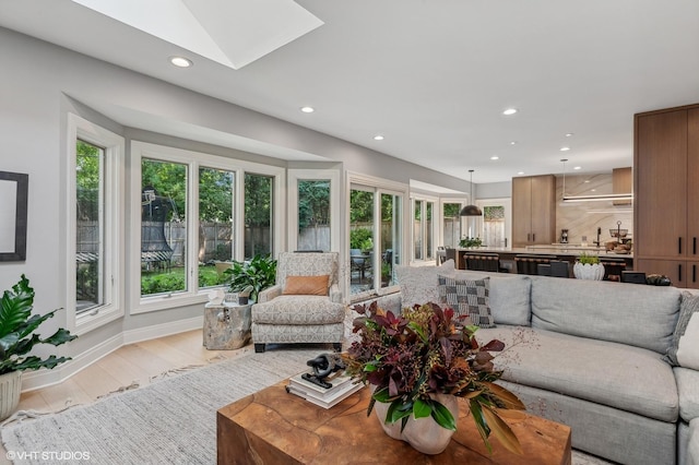 living area with baseboards, recessed lighting, a skylight, and light wood-style floors