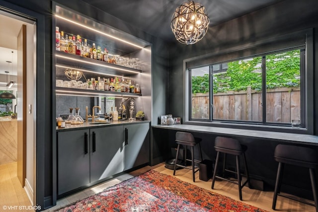 bar with an inviting chandelier, a sink, and wet bar