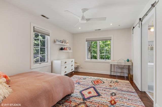 bedroom featuring a barn door, baseboards, visible vents, dark wood-style flooring, and recessed lighting