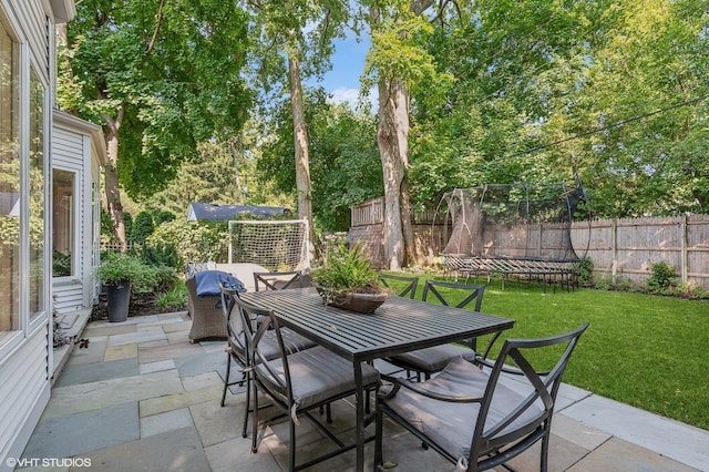 view of patio / terrace with a trampoline, outdoor dining area, and fence