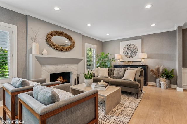 living area with crown molding, light wood-type flooring, a fireplace, and recessed lighting