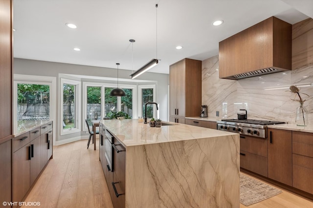 kitchen with stainless steel gas cooktop, a sink, a large island, and wall chimney exhaust hood