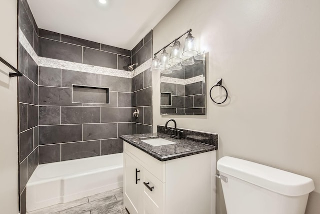 full bathroom with tiled shower / bath, vanity, and toilet