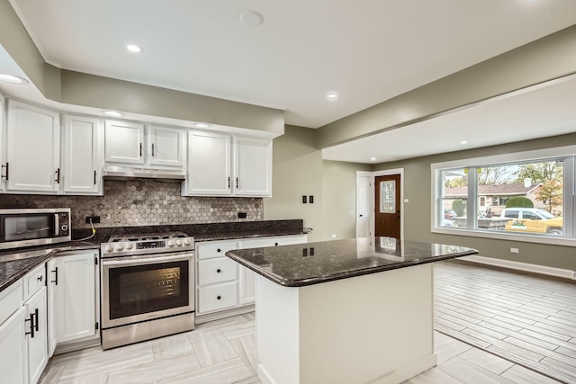 kitchen with dark stone countertops, stainless steel appliances, tasteful backsplash, and white cabinets