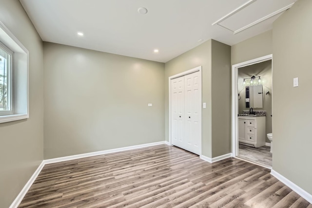 unfurnished bedroom with ensuite bath, sink, a closet, and light wood-type flooring