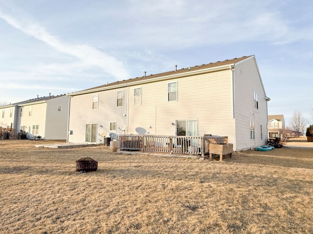 back of house featuring a fire pit and a lawn