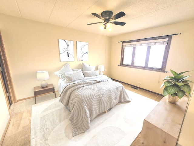 bedroom featuring ceiling fan, light hardwood / wood-style flooring, and a textured ceiling