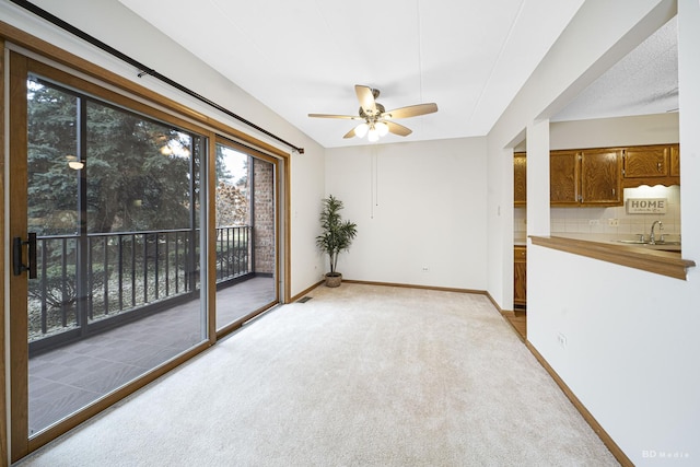 unfurnished room featuring ceiling fan, light colored carpet, and sink