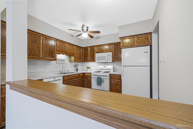 kitchen featuring tasteful backsplash, sink, white appliances, and kitchen peninsula