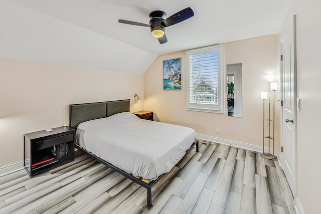 bedroom with a ceiling fan, vaulted ceiling, baseboards, and wood finished floors