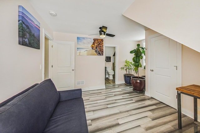 interior space with a ceiling fan, visible vents, baseboards, and wood finished floors