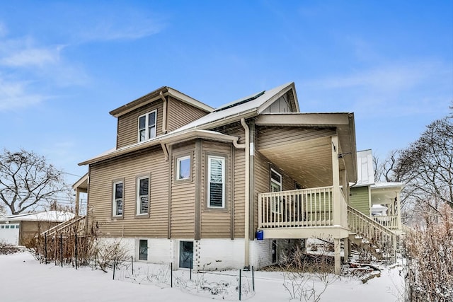 view of snow covered exterior with stairway and a porch