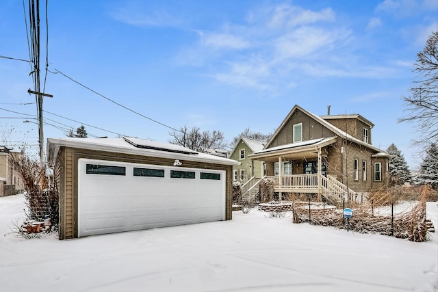 view of front of home featuring a garage, a porch, and an outbuilding