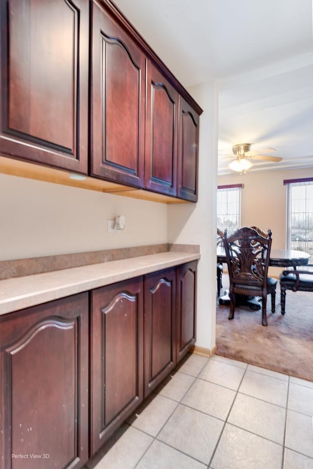 kitchen with ceiling fan, dark brown cabinetry, and light carpet