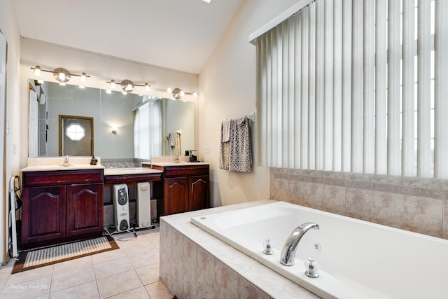 bathroom with vanity, tile patterned flooring, vaulted ceiling, and tiled bath