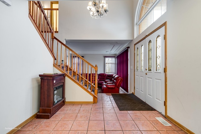 tiled foyer featuring a towering ceiling and a notable chandelier