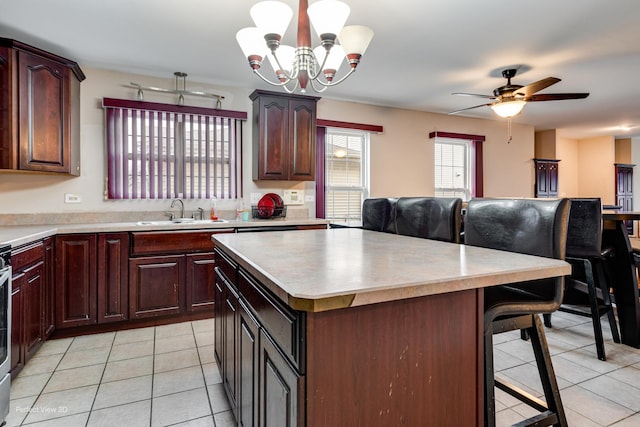 kitchen featuring pendant lighting, sink, light tile patterned floors, a breakfast bar, and a kitchen island