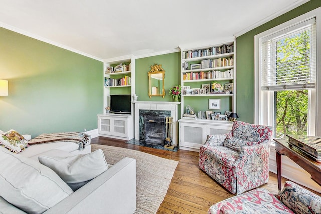 living room with a high end fireplace, hardwood / wood-style flooring, crown molding, and built in shelves