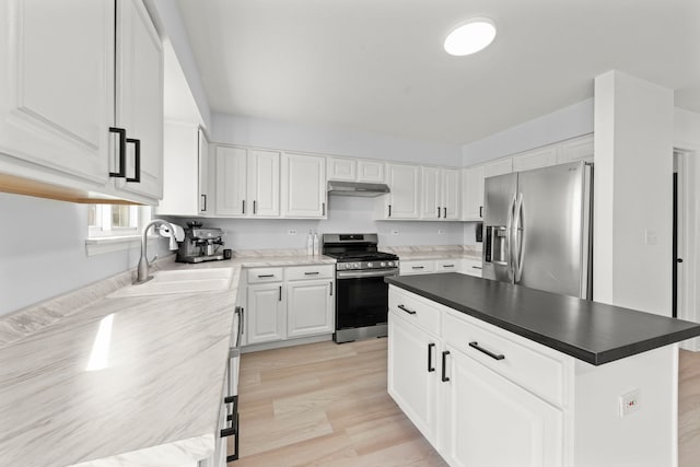 kitchen featuring under cabinet range hood, stainless steel appliances, a kitchen island, a sink, and white cabinetry