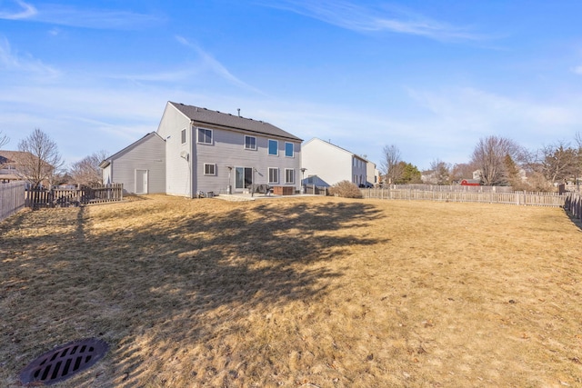 rear view of property featuring a fenced backyard and a yard