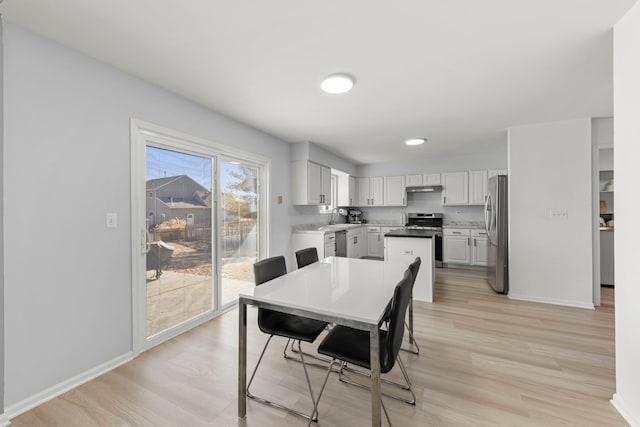 dining area featuring light wood finished floors and baseboards