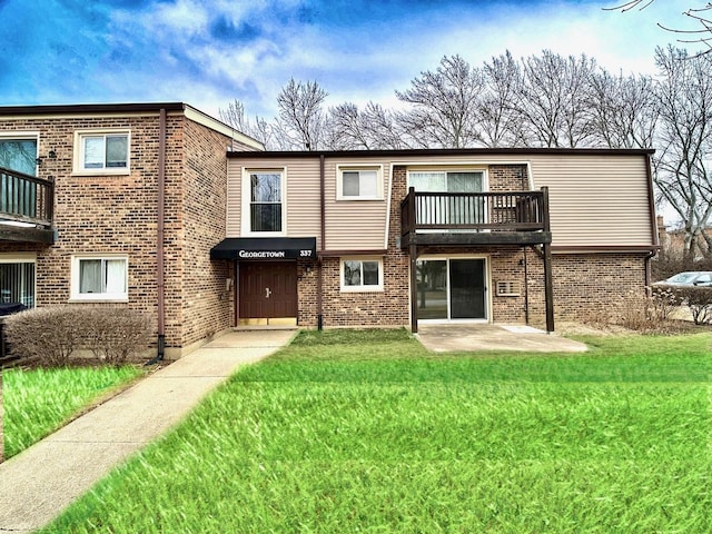 rear view of property featuring a balcony, a patio area, and a lawn