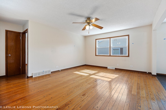 unfurnished room with baseboards, visible vents, a textured ceiling, and wood finished floors