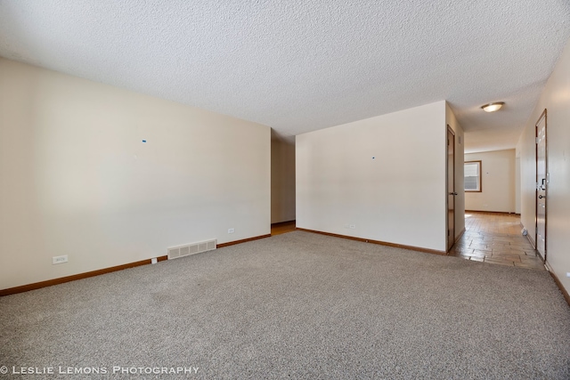 unfurnished room featuring baseboards, visible vents, light colored carpet, and a textured ceiling