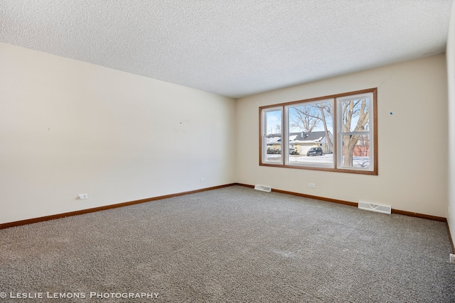 unfurnished room with visible vents, baseboards, carpet floors, and a textured ceiling