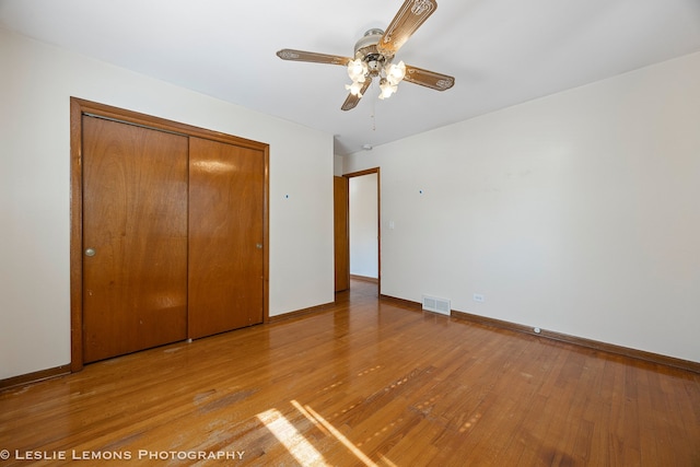 unfurnished bedroom featuring visible vents, a ceiling fan, light wood finished floors, baseboards, and a closet