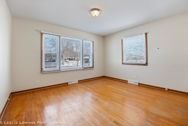 unfurnished room featuring visible vents, light wood-style floors, and baseboards