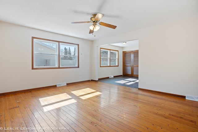 spare room with baseboards, visible vents, a textured ceiling, and light wood-type flooring