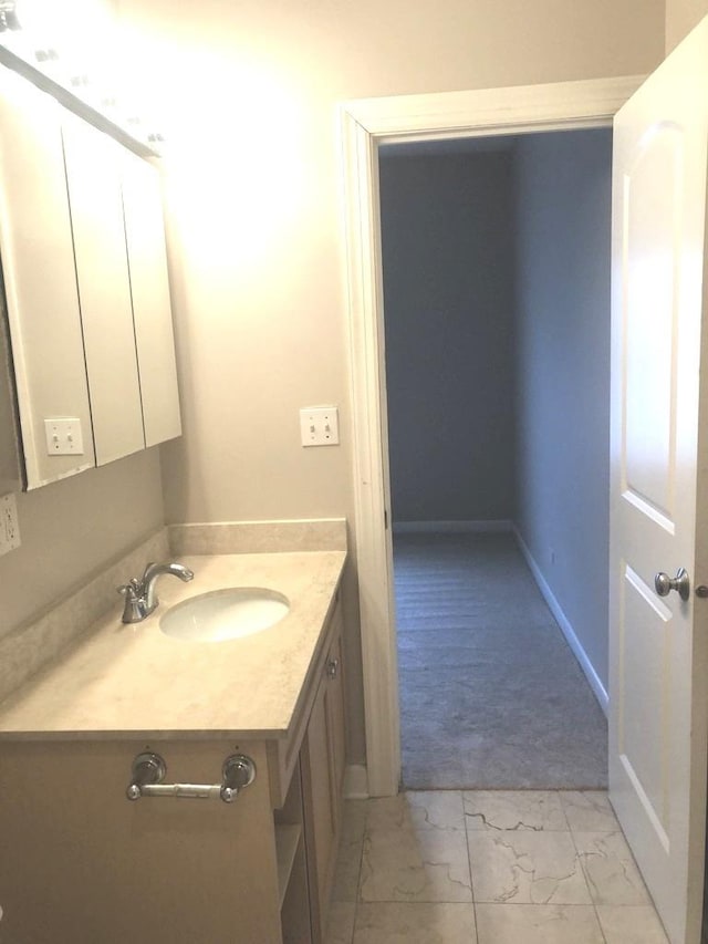 bathroom with baseboards, marble finish floor, and vanity