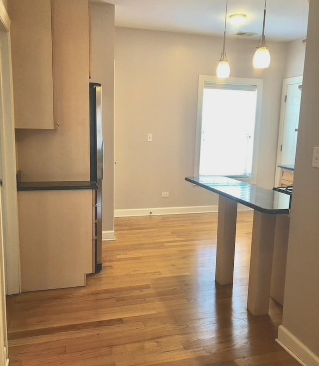 kitchen with visible vents, light wood finished floors, dark countertops, and freestanding refrigerator