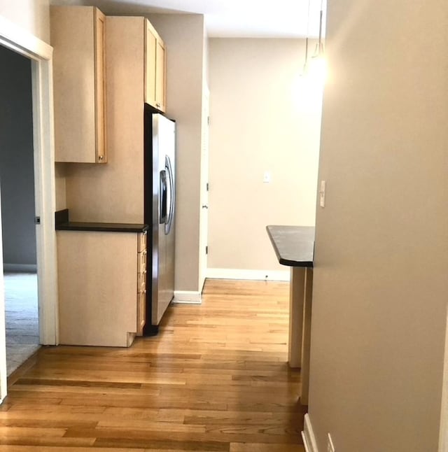 hallway featuring light wood-style flooring and baseboards