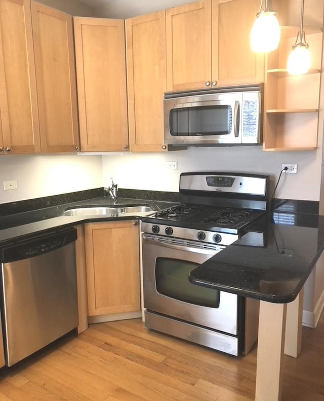 kitchen featuring light brown cabinetry, stainless steel appliances, light wood-type flooring, and a sink