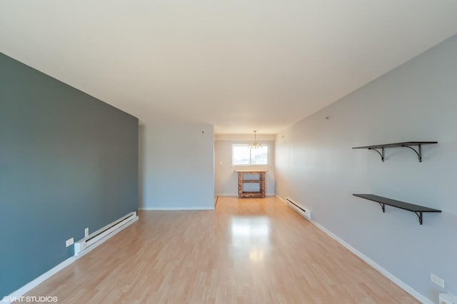 unfurnished living room with a baseboard heating unit, a notable chandelier, and light hardwood / wood-style floors