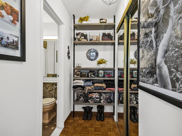 walk in closet with dark parquet flooring