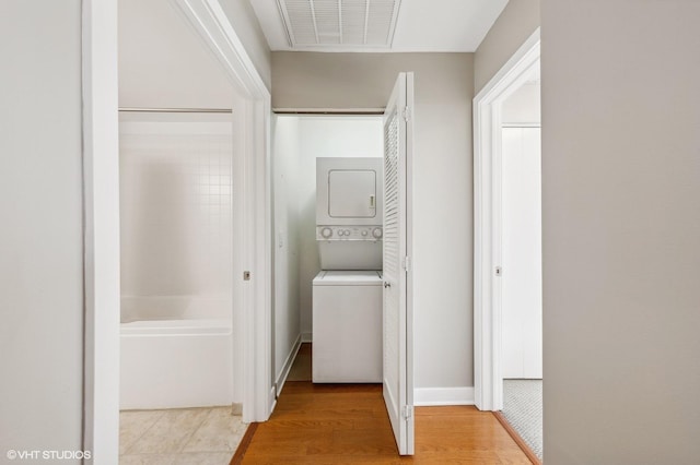 clothes washing area featuring stacked washer and dryer and light wood-type flooring