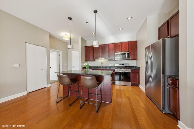 kitchen featuring pendant lighting, stainless steel appliances, a center island, and light hardwood / wood-style flooring