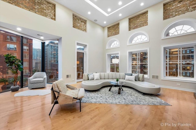 living room featuring a towering ceiling and light hardwood / wood-style flooring