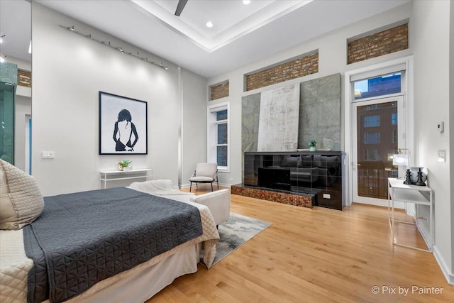 bedroom featuring a tray ceiling, wood-type flooring, and a high ceiling